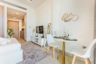a white living room with a table and chairs at Studio Near Dubai Creek, Dubai Frame & Downtown, Farhad Azizi, Al Jaddaf by Deluxe Holiday Homes in Dubai