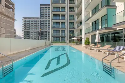a swimming pool with chairs and a building at 1 Bedroom in Binghatti Lavender in Dubai