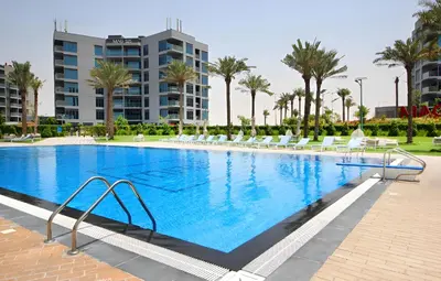 a large swimming pool with chairs and palm trees at Prival - Sunlit Serenity 1BR Retreat in Dubai