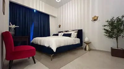 a bedroom with a bed and a red chair at Bespoke Holiday Homes - Stylish 2BR in Oxford 212 JVC in Dubai