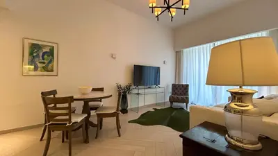 a living room with a couch and a table with chairs at Bespoke Holiday Homes - Stylish 2BR in Oxford 212 JVC in Dubai