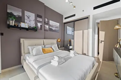 a bedroom with a large white bed with towels on it at Stylish 1BR w Skyline Views & Balcony in Dubai