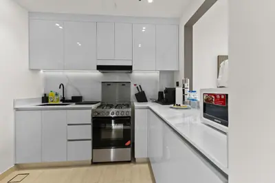 a white kitchen with a stove and white cabinets at Stylish 1BR w Skyline Views & Balcony in Dubai