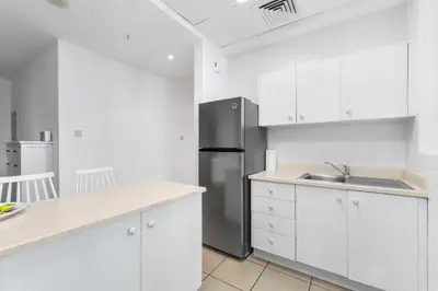 a kitchen with white cabinets and a stainless steel refrigerator at Stylish 1BR in Marina, Balcony Near JBR in Dubai
