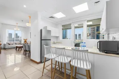 a kitchen with a bar with stools and a refrigerator at Stylish 1BR in Marina, Balcony Near JBR in Dubai