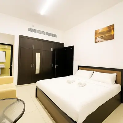a bedroom with a large white bed and a chair at Single Bed In Twin Room With Balcony For Female Guests Only in Dubai