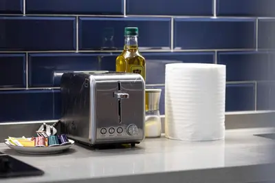 a toaster sitting on a counter with a bottle of wine at Cosy Studio, 7-min walk Burj Khalifa and Dubai Mall in Dubai