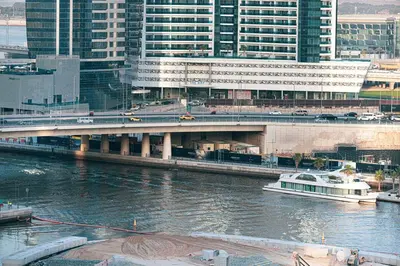 a bridge over a river with a boat in a city at Cosy Studio, 7-min walk Burj Khalifa and Dubai Mall in Dubai