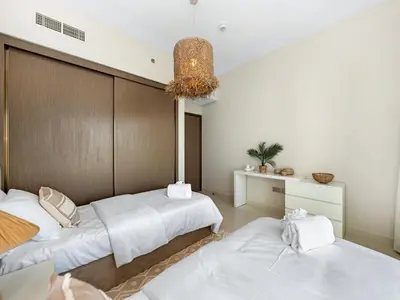 a bedroom with two beds and a chandelier at Luxury Spacious 2 Bedroom Private Beach and Views in Dubai