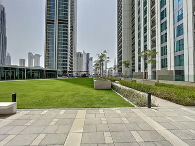 a park in the middle of a city with tall buildings at Downtown Views 3 - Chic One Bed with City Views in Dubai