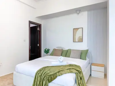 a white bedroom with a large white bed with green pillows at Upgrade Unit for 6 pax with Sea View Ideal Location Near Beach Big Balcony in Dubai