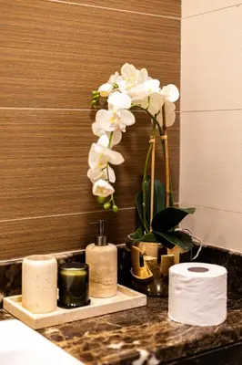 a bathroom counter with towels and a vase with white flowers at Stunning 1BR with Breathtaking Views Dubai Marina in Dubai