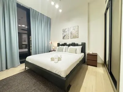 a bedroom with a large bed with two candles on it at DVR 1BR Apartment Available in Binghatti Corner in Dubai