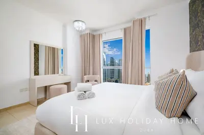 a bedroom with a large white bed and a window at LUX The Burj Khalifa Fountain View Suite 3 in Dubai