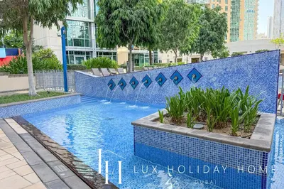 a swimming pool with a blue tile wall and waterfalls at LUX The Burj Khalifa Fountain View Suite 3 in Dubai