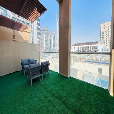 a balcony with chairs and a view of a city at Modern 1BR w Pool and Parking At Roxana Residence in Dubai