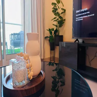 a glass table with a vase on top of it at Modern 1BR w Pool and Parking At Roxana Residence in Dubai