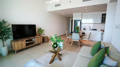 a living room with a couch and a tv and a kitchen at Luxurious 1BR High Floor Skyline View Downtown in Dubai