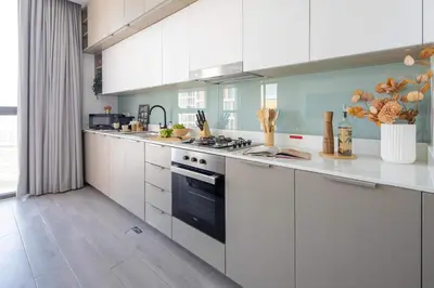 a kitchen with white cabinets and a stove top oven at Frank Porter - Noor 3 Midtown in Dubai
