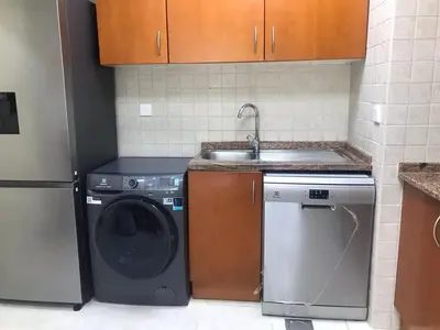 a kitchen with a washing machine and a sink at Cozy Bedroom Retreat in Green Community Pool View in Dubai