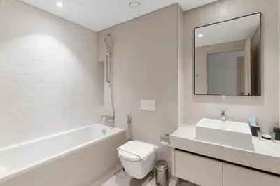 a white bathroom with a tub and a toilet and a sink at Luxury Stay at Marina Vista, Dubai Harbour in Dubai