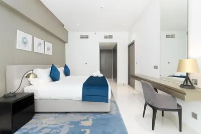 a bedroom with a bed and a desk and a chair at BellaViu Holiday Homes-From City Rush to Calm -2BR Retreat in DAMAC Prive in Dubai