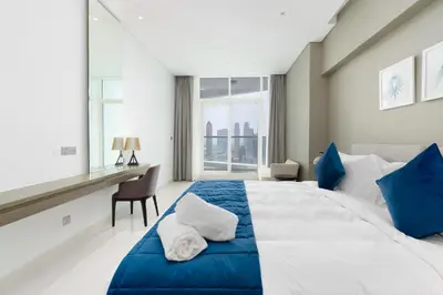 a bedroom with a large bed and a desk at BellaViu Holiday Homes-From City Rush to Calm -2BR Retreat in DAMAC Prive in Dubai
