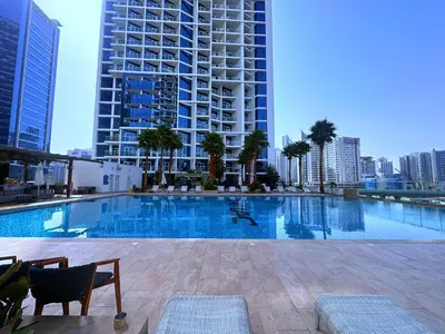a large swimming pool in a city with tall buildings at BellaViu Holiday Homes-From City Rush to Calm -2BR Retreat in DAMAC Prive in Dubai