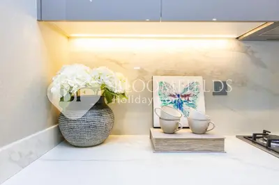 a kitchen counter with a vase of flowers and a picture at Bloomfields 1br Azizi Farhad Burj View Bliss in Dubai