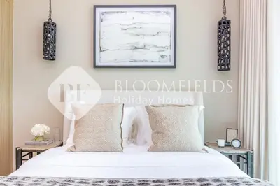 a bedroom with a bed with white sheets and pillows at Bloomfields 1br Azizi Farhad Burj View Bliss in Dubai