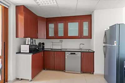 a kitchen with wooden cabinets and a refrigerator at 2-Bedroom Apartment Near To The Beach in Sadaf in Dubai