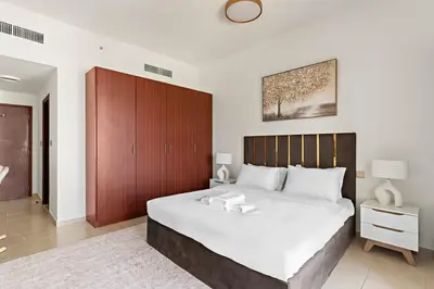 a bedroom with a large bed with a wooden headboard at 2-Bedroom Apartment Near To The Beach in Sadaf in Dubai