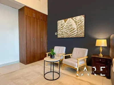 a living room with two chairs and a table at Rare Holiday Homes - Near Miracle Garden - Dubai Sports City - Elite Residence - R1108 in Dubai
