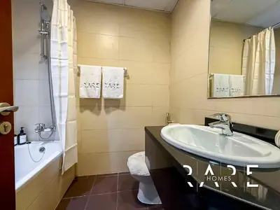a bathroom with a sink and a tub and a toilet at Rare Holiday Homes - Near Miracle Garden - Dubai Sports City - Elite Residence - R1108 in Dubai