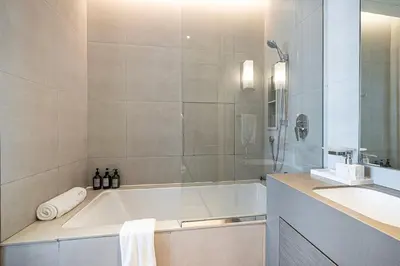 a white bathroom with a tub and a sink at Beachfront Bliss - Marina View - JBR The Address By ĀYA Boutique in Dubai