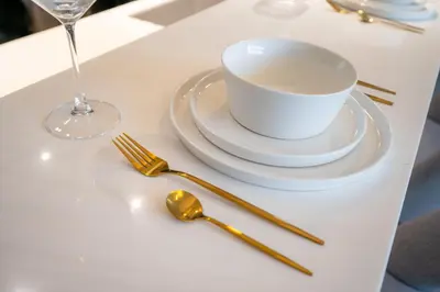 a white table with a plate and a cup and fork at High Floor With Marina View in Dubai