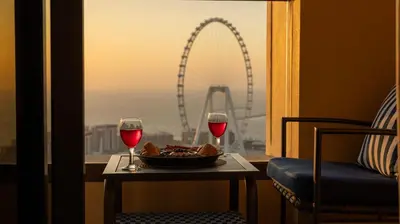 a table with a bowl of food and two glasses of wine at 2Br Panoramic sea view, Ain Dubai, Palm, JBR beach in Dubai