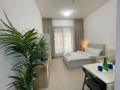a living room with a couch and a palm tree at Nice Studio On Marina Walk in Dubai