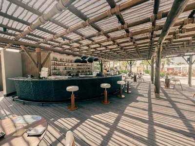 a patio with a bar with stools and tables at Palm Jumeirah Beach Paradise at Fairmont Residence in Dubai