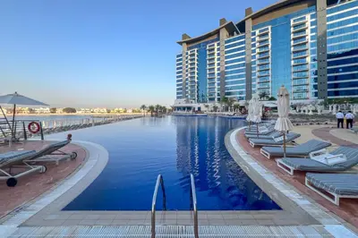 a pool at a resort with chairs and umbrellas at Resort Style 2BR Pool Access Private Beach in Dubai