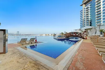 a swimming pool with a bridge over a body of water at Resort Style 2BR Pool Access Private Beach in Dubai
