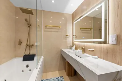 a bathroom with a tub and a sink and a mirror at Resort Style 2BR Pool Access Private Beach in Dubai