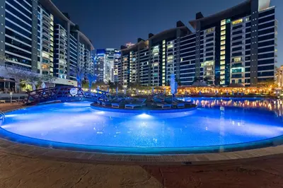 a large swimming pool in a city at night at Resort Style 2BR Pool Access Private Beach in Dubai