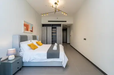 a bedroom with a large bed with yellow pillows at Brand New Luxury One Bedroom in Dubai
