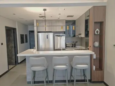 a kitchen with a counter with stools and a refrigerator at Brand New Luxury One Bedroom in Dubai