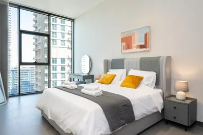 a bedroom with a large bed with yellow pillows at Brand New Luxury One Bedroom in Dubai