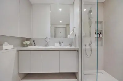 a white bathroom with a shower and a sink at Brand new and stylish 2BR with stunning views - Creek Palace in Dubai