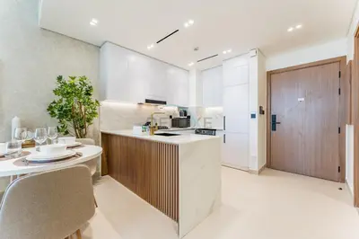 a kitchen with white cabinets and a wooden door at Community Views 1BR Next to Mall and Park, Binghatti Amber, Jumeirah Village Circle by Deluxe Holiday Homes in Dubai