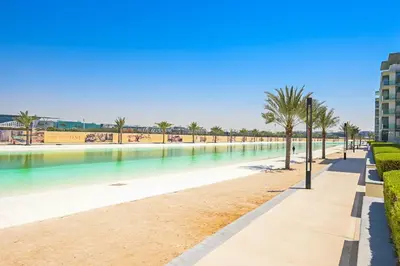 a swimming pool with palm trees and a sidewalk at Crystal Escape 1BR Lagoon Access in Dubai