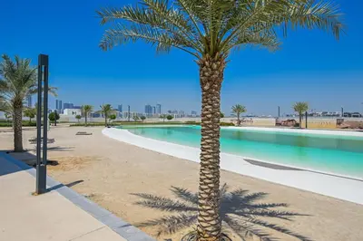 a palm tree in front of a swimming pool at Crystal Escape 1BR Lagoon Access in Dubai